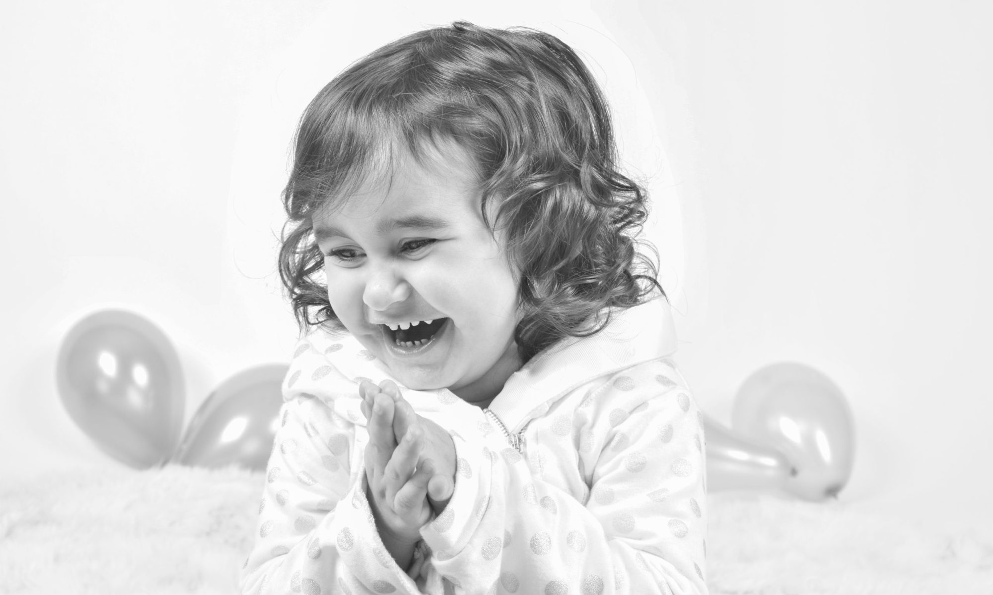 Niña pequeña mirando a cámara en un retrato infantil en blanco y negro sobre fondo blanco.